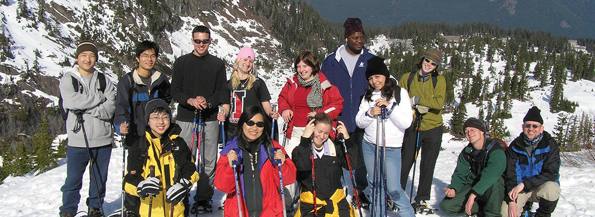 International students on a ski trip posing for a picture on a snowy mountain