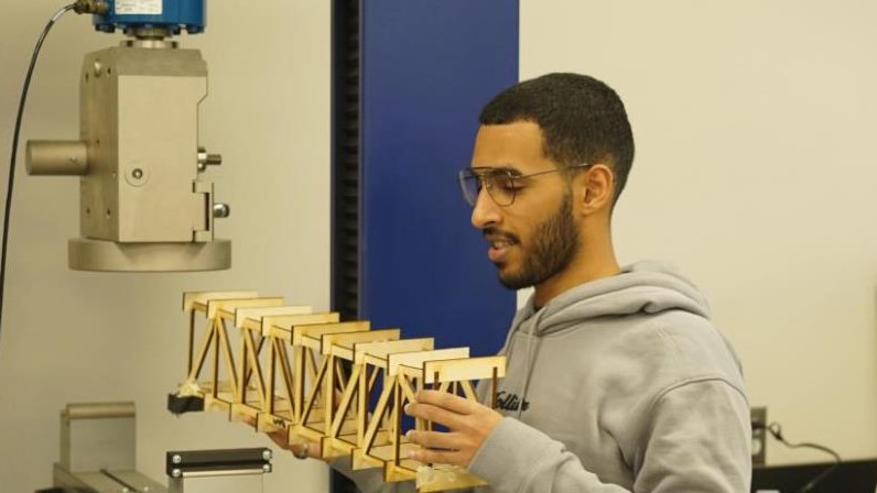 Engineering student holding bridge model