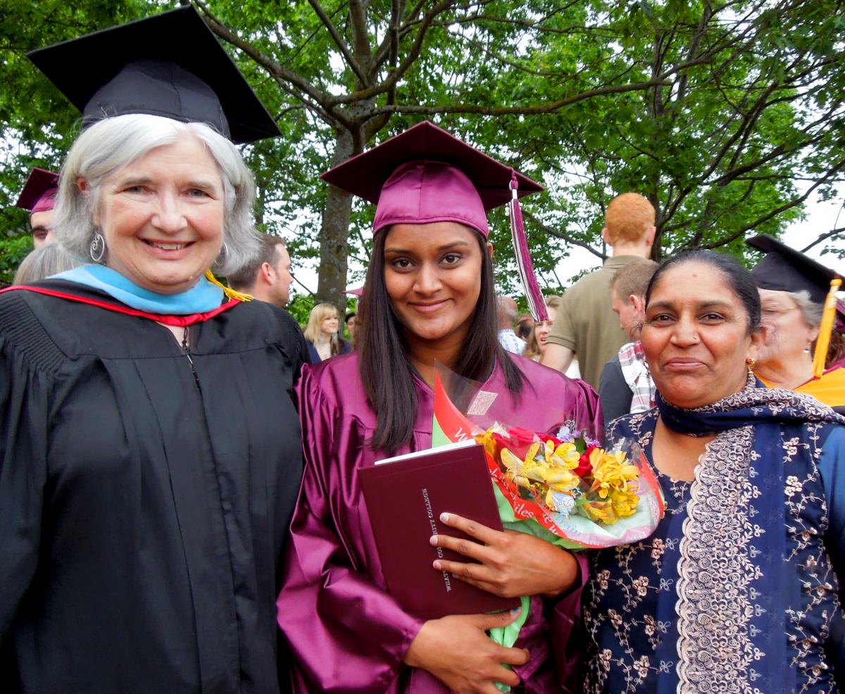 An image of an international students graduate standing next to her professor and mother