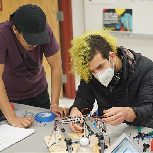 Two Whatcom Community College engineering students working in a classroom on a circuit board.