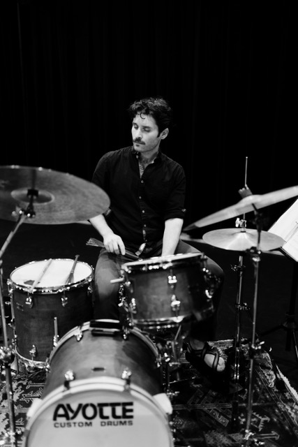 Faculty member Christian Casolary sitting behind a drumset playing