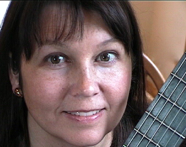 Close-up photo of faculty member Deborah Anderson holding a classical guitar