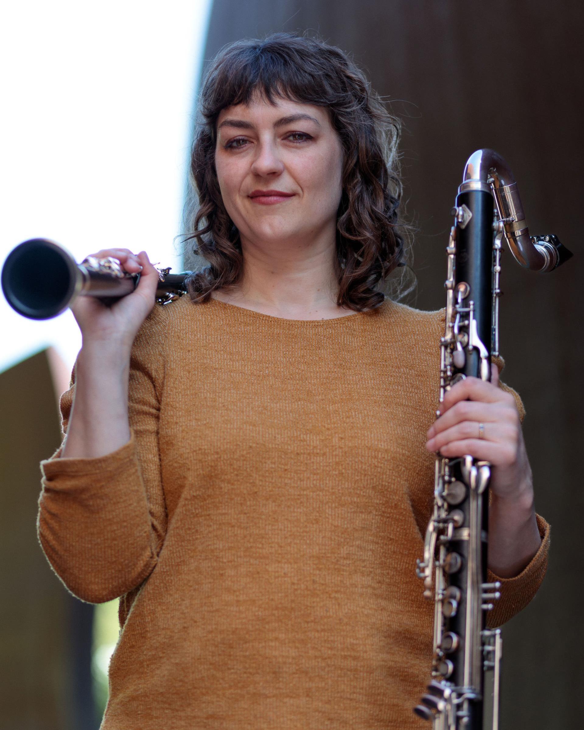 Faculty member Rachel Yoder outdoors holding two clarinets