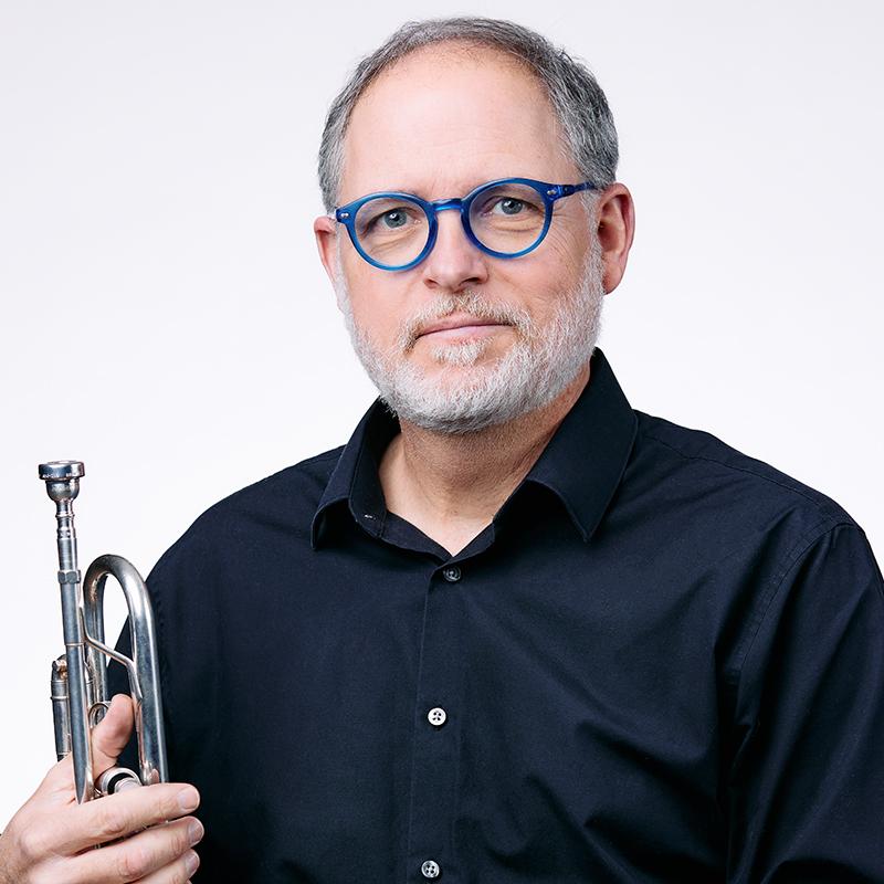 Faculty member Vincent Green against a white background holding a trumpet