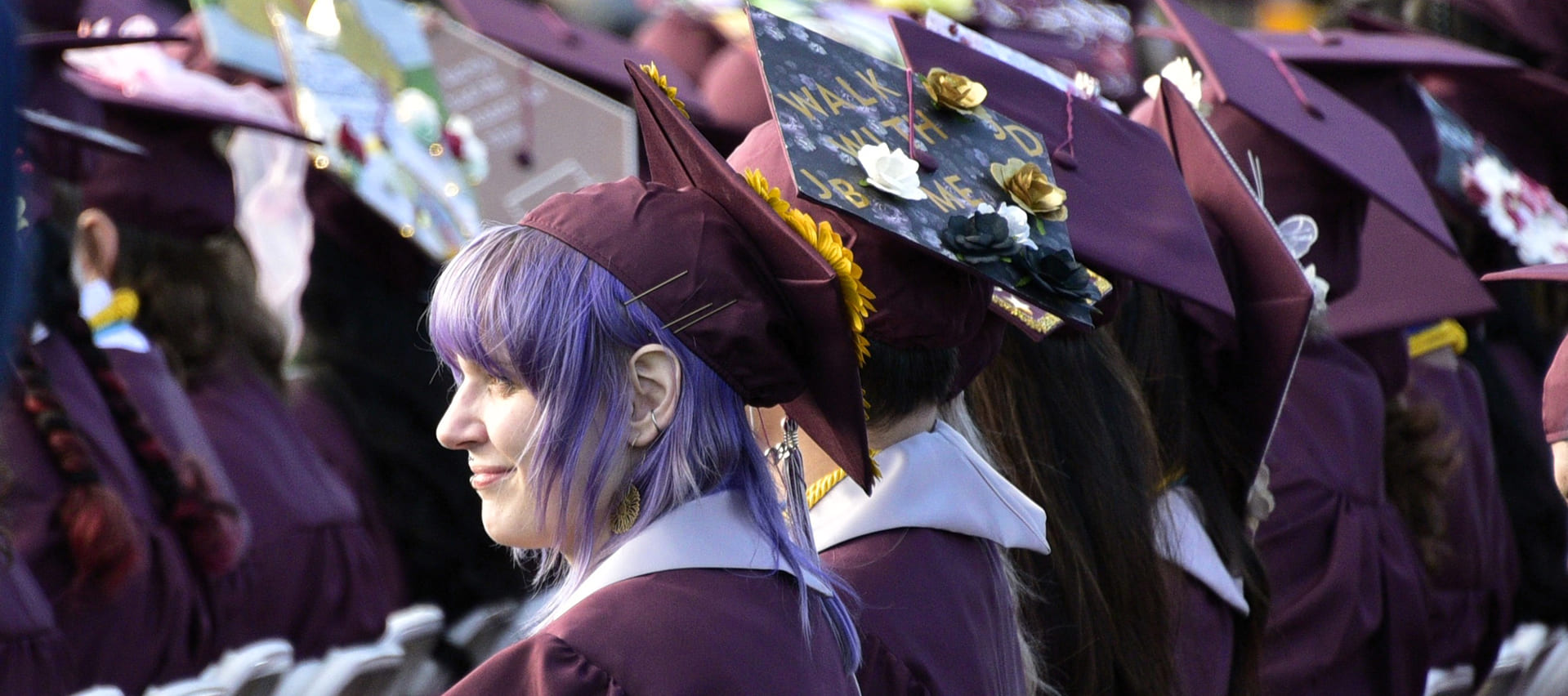 Up close photograph of graduates sitting during commencement in their caps and gowns