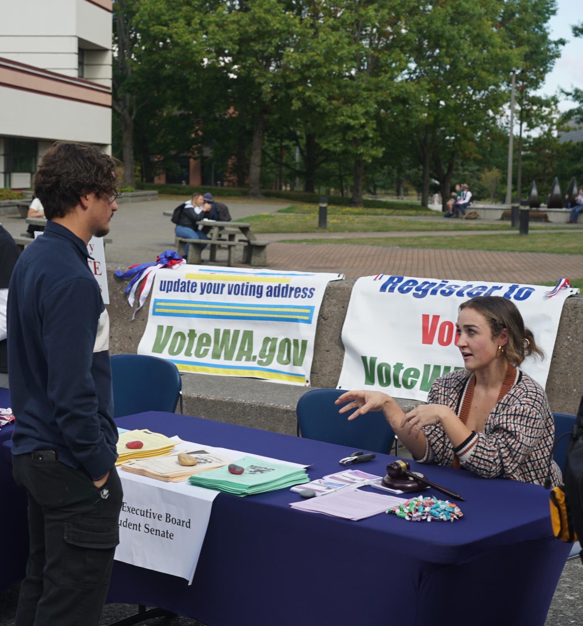 Photo of ASWCC President speaking with a student about voting while tabling at the Welcome Back BBQ