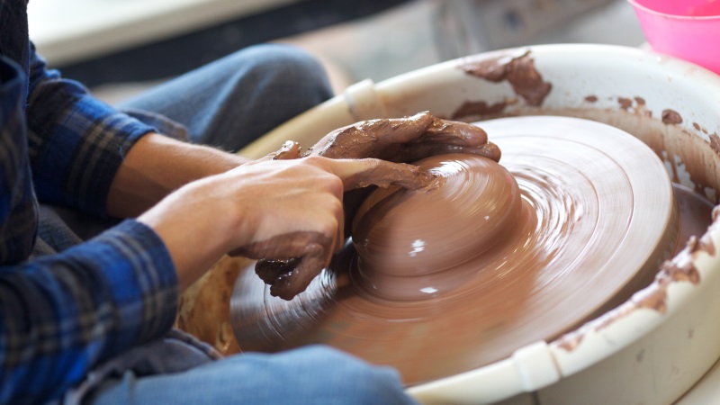 Student making a pot on a pottery wheel