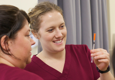 Nursing students smiling with syringe